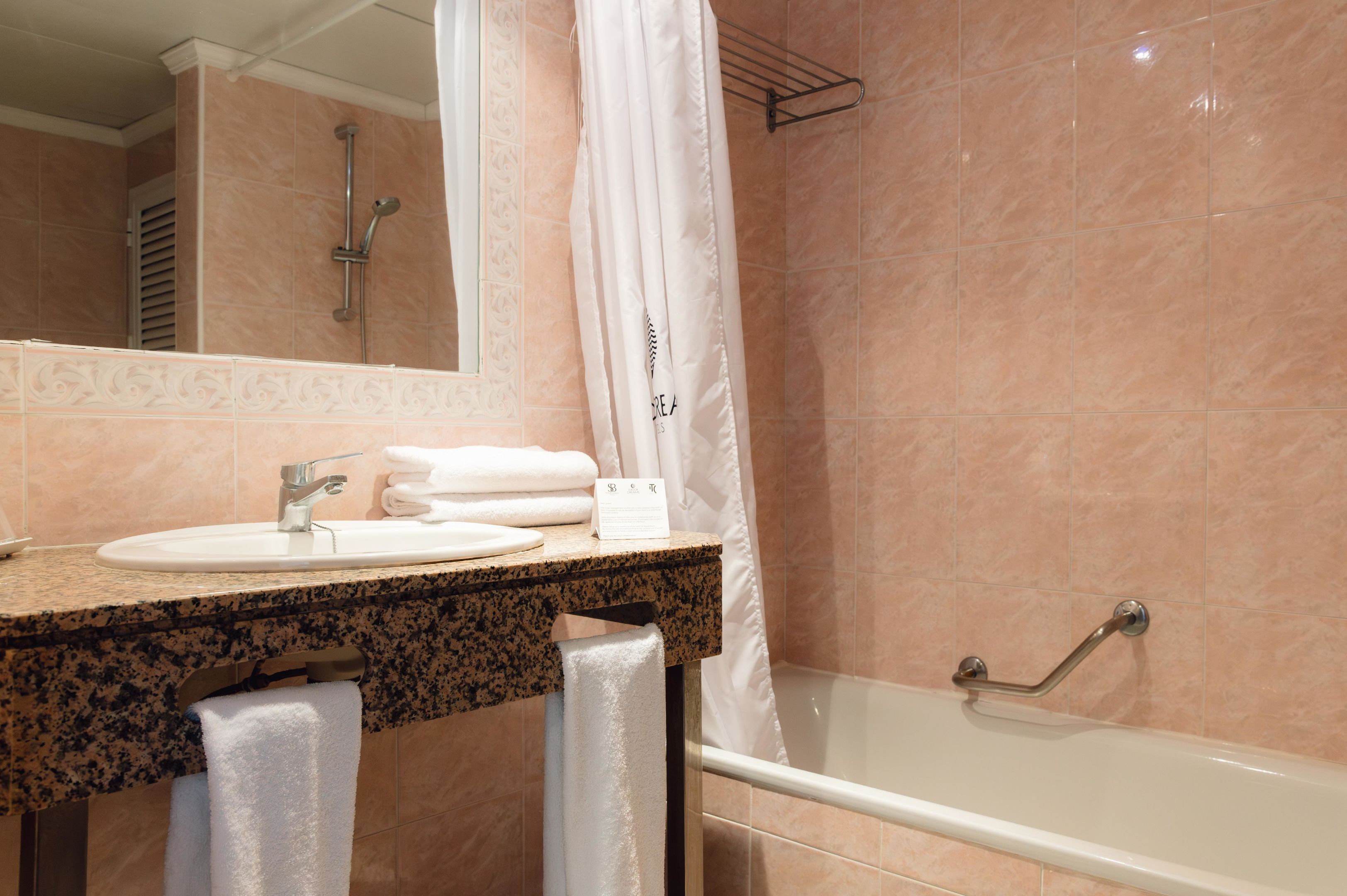 A bathroom with a sink, mirror, shower, and bathtub.