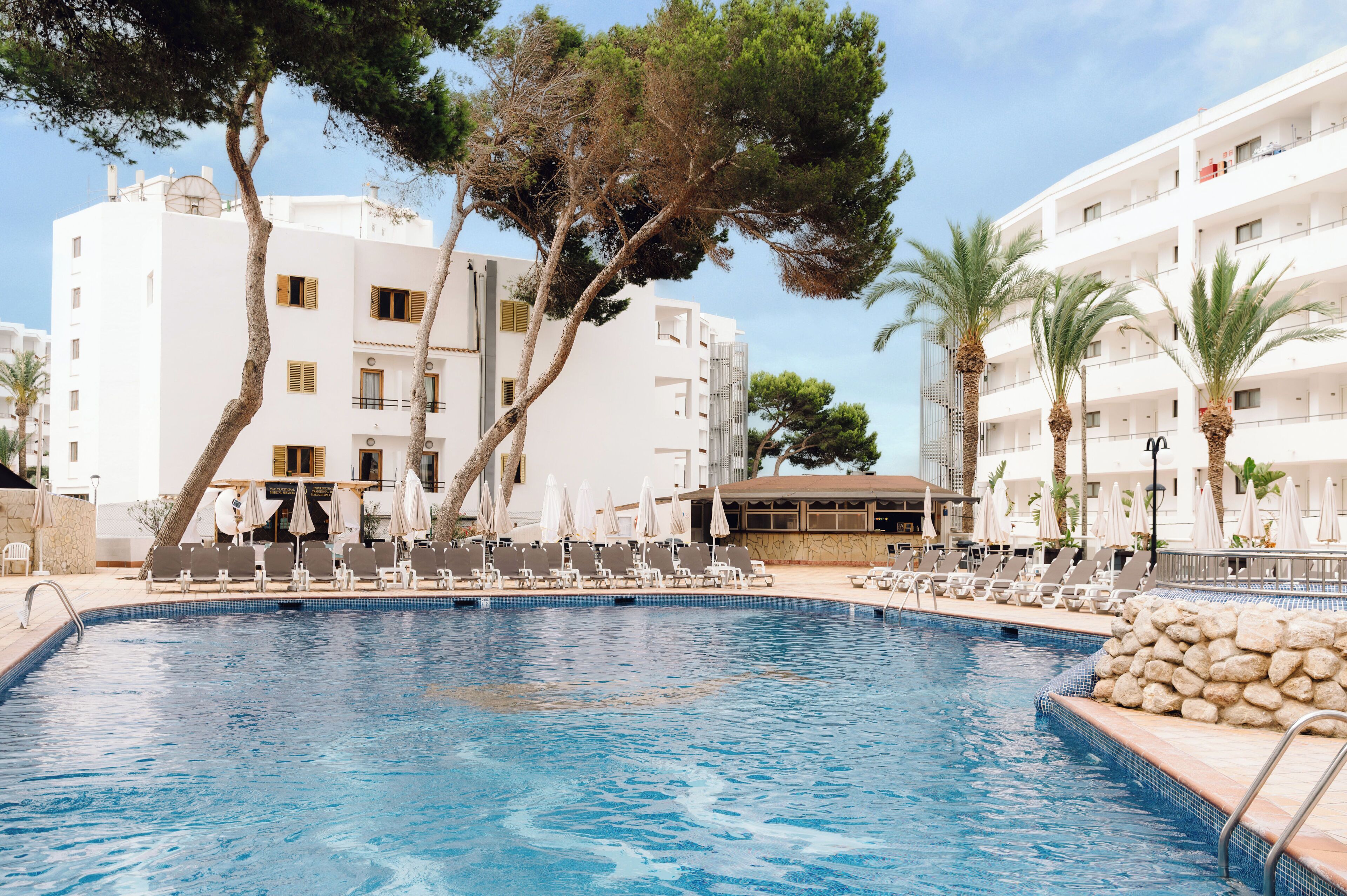 Una piscina al aire libre, sombrillas, tumbonas