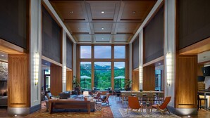 Un hall d’entrée spacieux avec un grand espace salon, une table à manger et une vue sur les montagnes grâce à de grandes fenêtres.