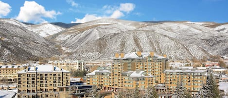 A hotel complex with multiple buildings, a snow-covered landscape, and mountains in the background.