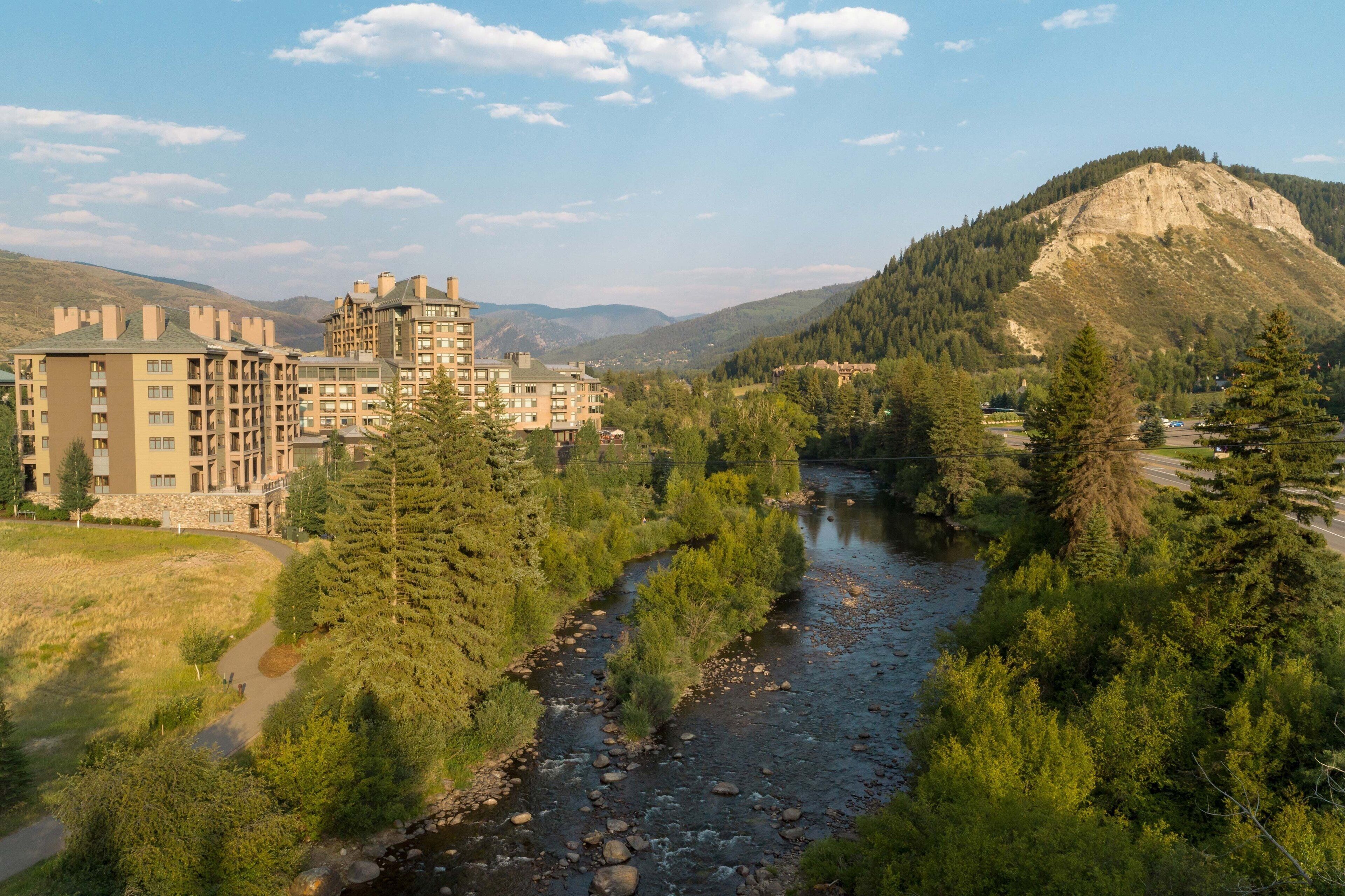 A hotel with multiple buildings, a river, and a mountainous backdrop.