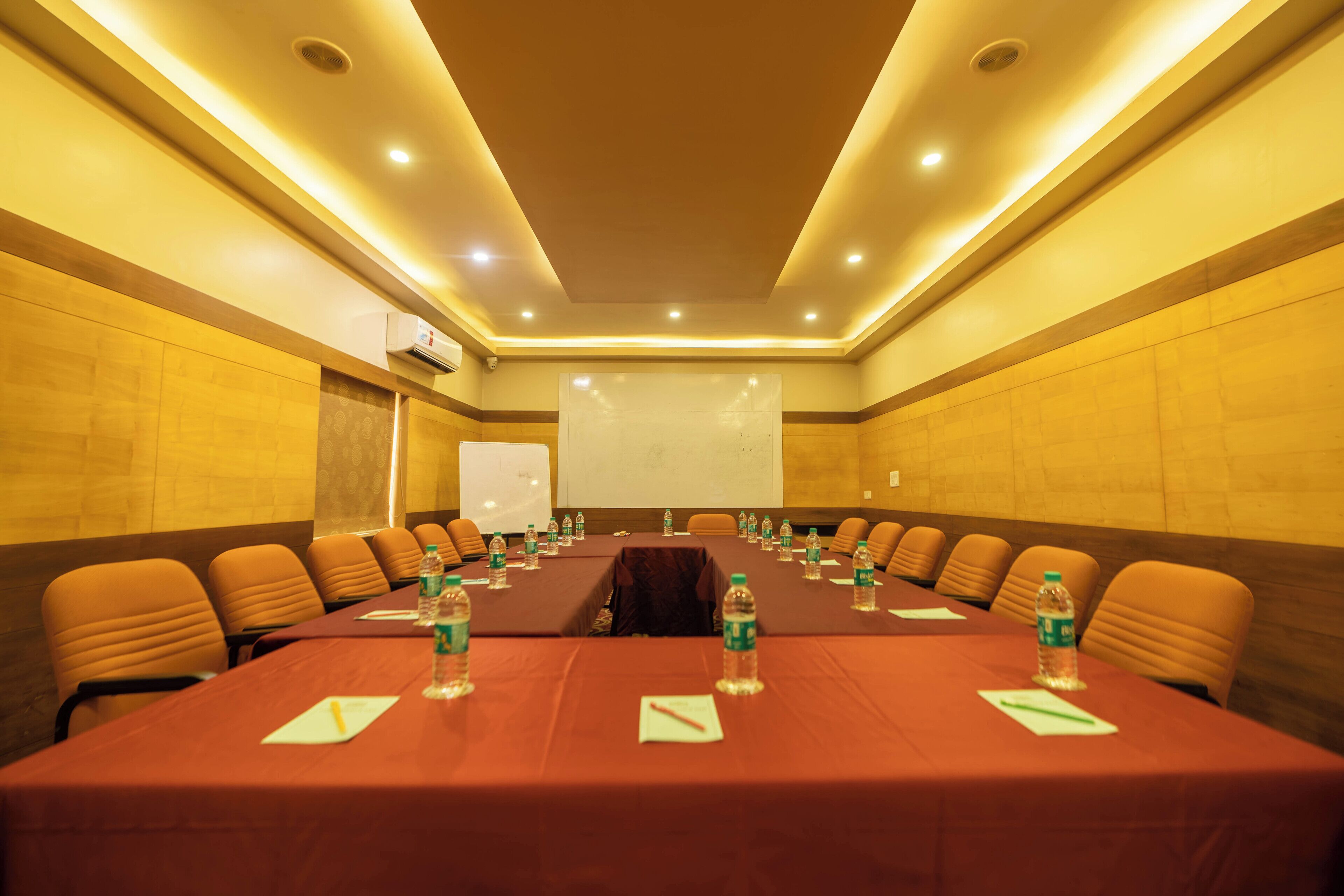 A conference room with a long table, chairs, and a projector screen.