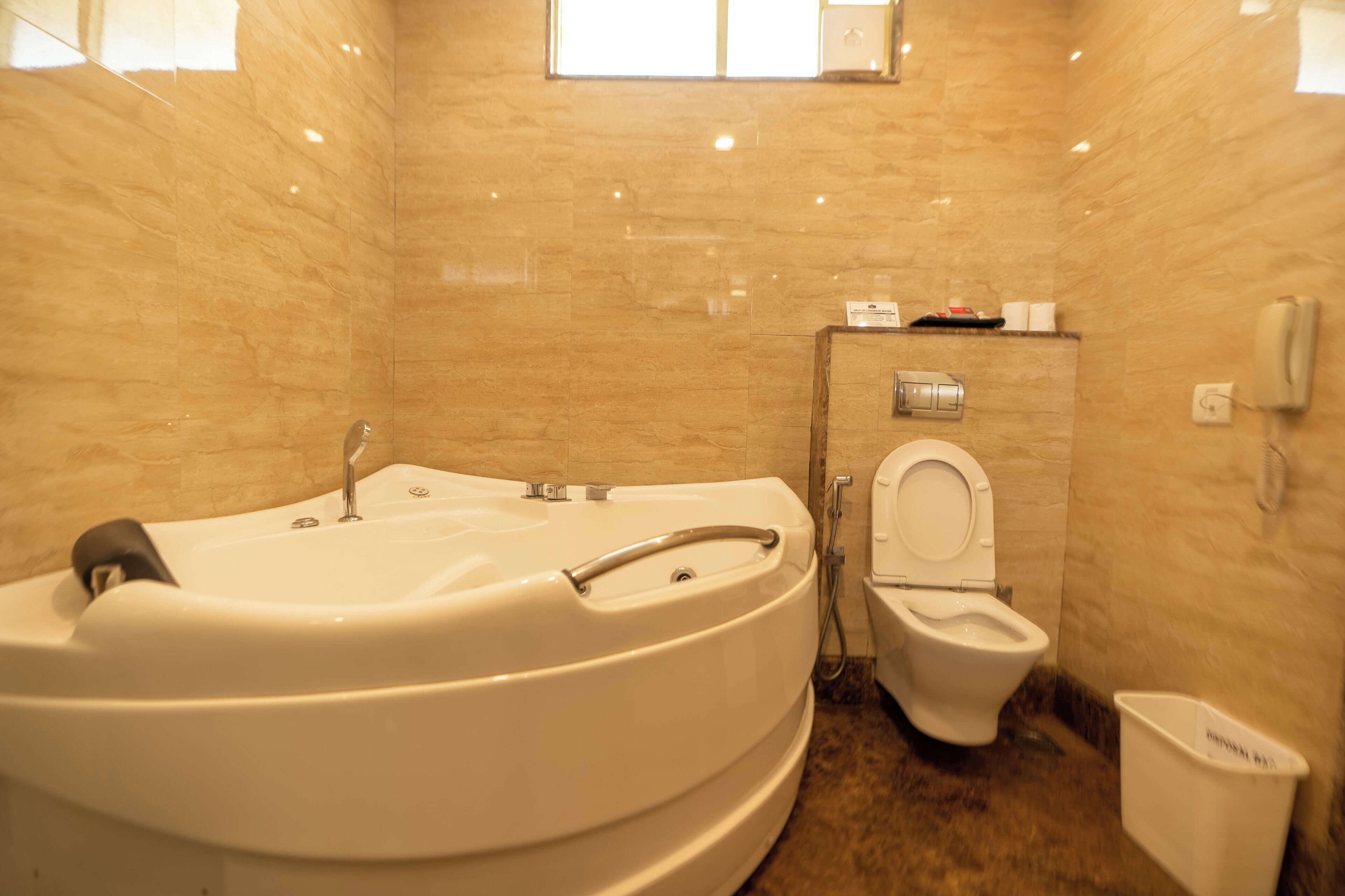 A bathroom with a bathtub, toilet, and a trash bin.