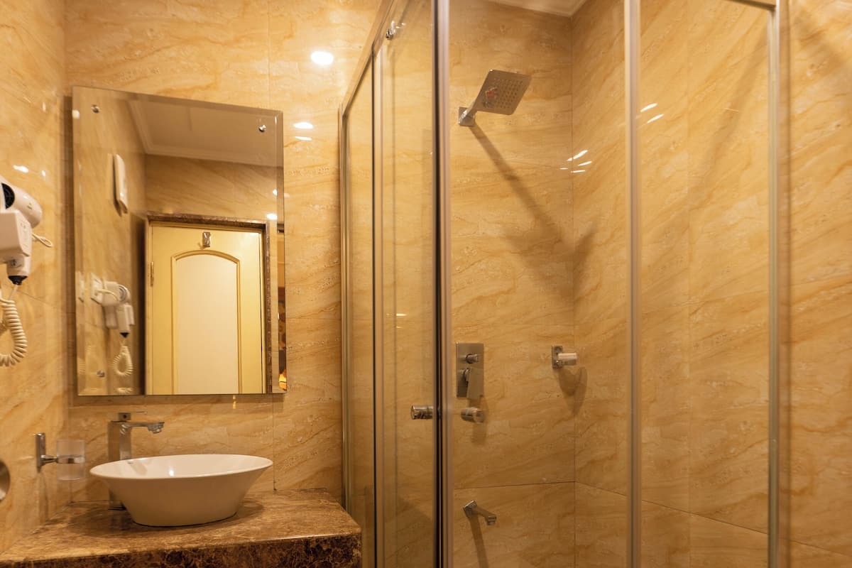 A bathroom with a glass-enclosed shower, a sink, and a mirror.