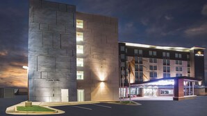 Un hôtel moderne à la façade sobre, doté de nombreuses fenêtres et d’une entrée bien éclairée.
