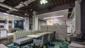 Un espace de détente moderne comprenant un canapé, des fauteuils et des tables, agrémenté d’un tapis à motifs et d’un luminaire décoratif au plafond.