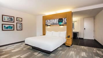 A hotel room with a large bed, a wooden headboard, and framed pictures on the wall.