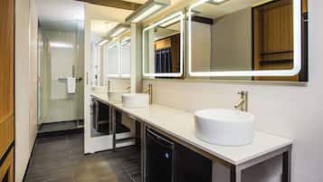 A modern bathroom with a glass shower enclosure, a white sink with a gold faucet, and a mirror with integrated lighting.