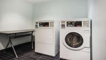A laundry area with two front-loading washing machines and a table.