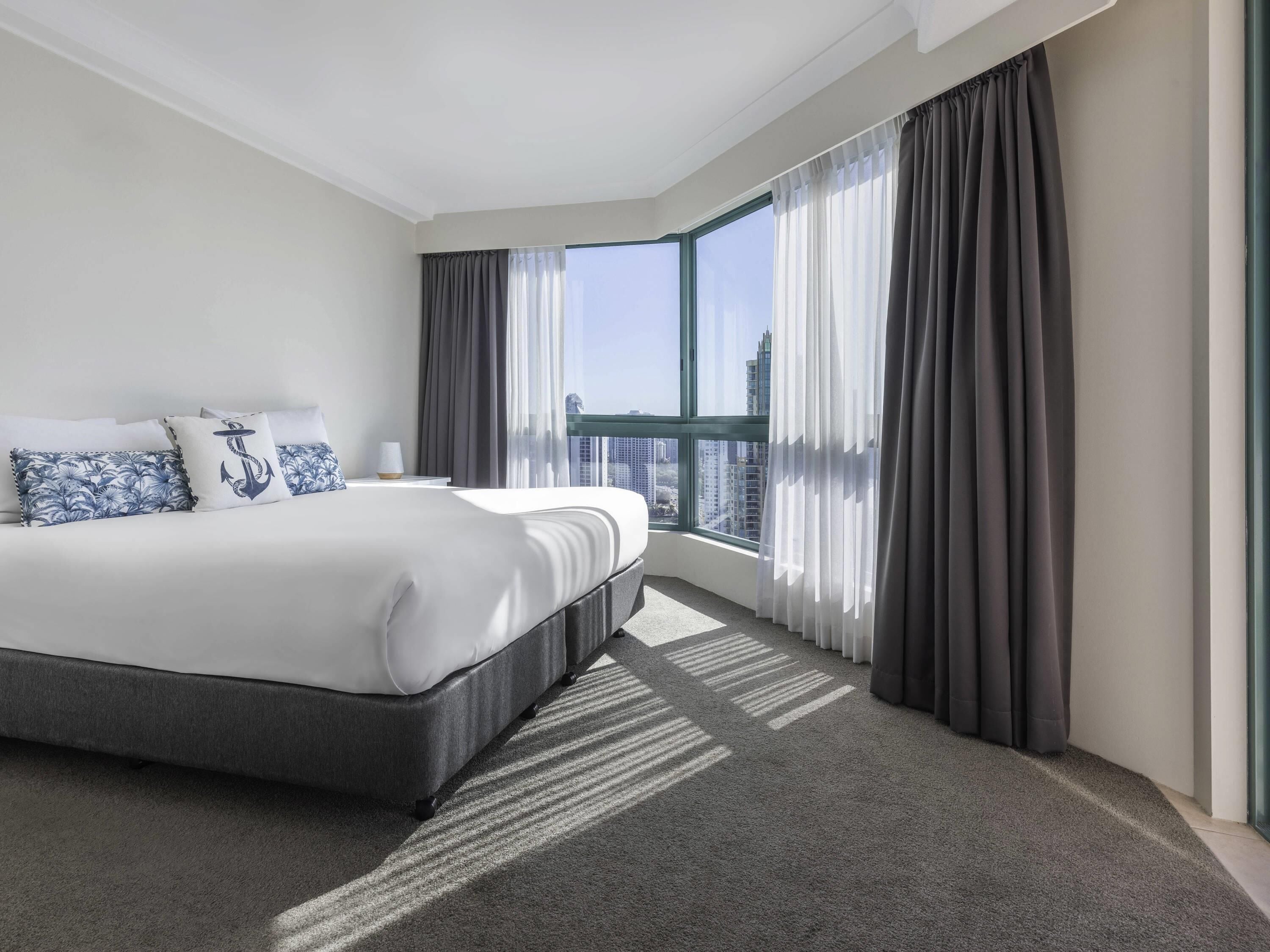 A modern hotel room with a large bed, a view of the city, and a balcony.