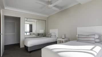 Une chambre d’hôtel avec deux lits, un ventilateur de plafond, un miroir et une petite table de chevet.