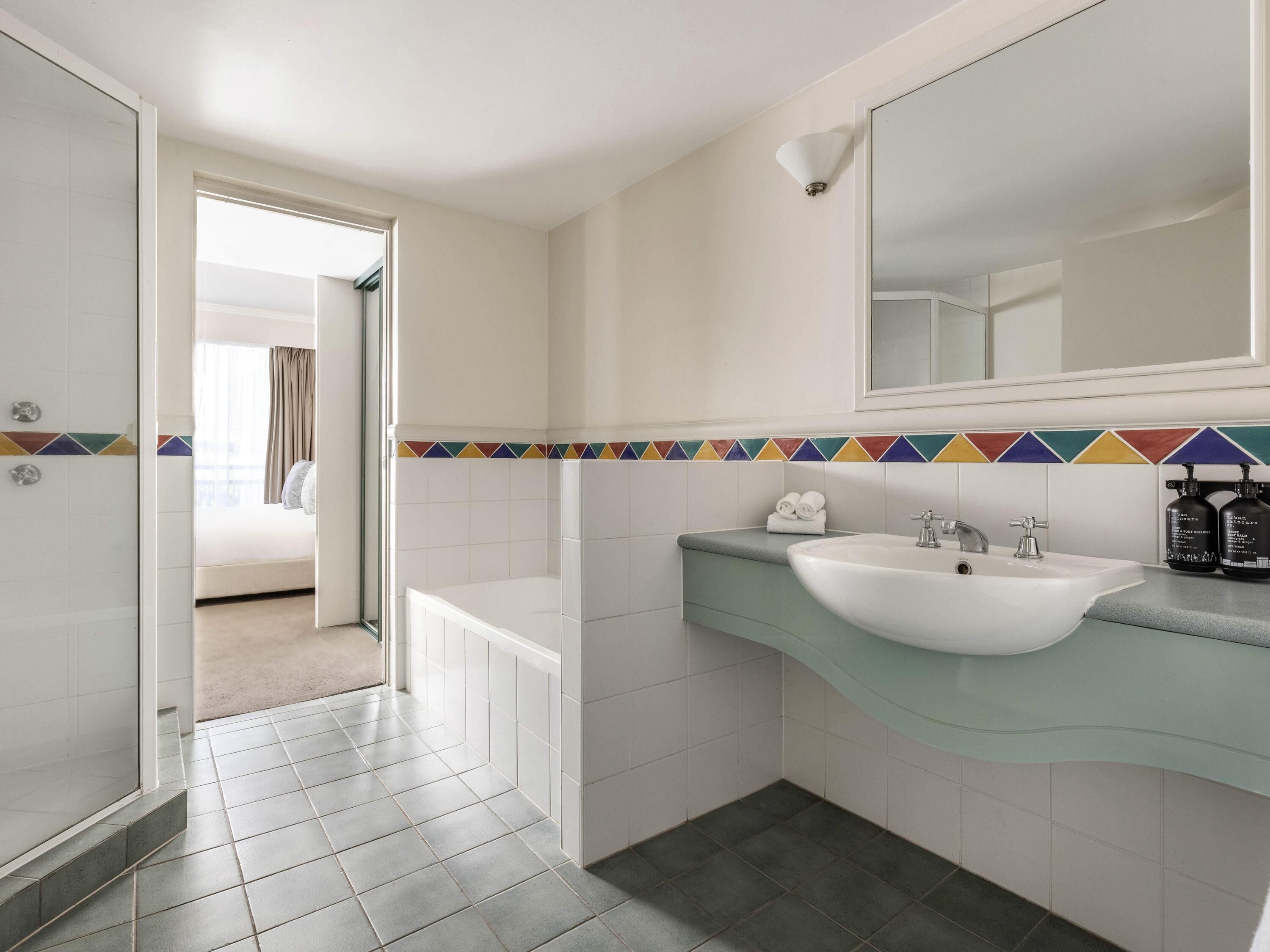 Un bagno con un lavandino bianco, uno specchio e un pavimento piastrellato.