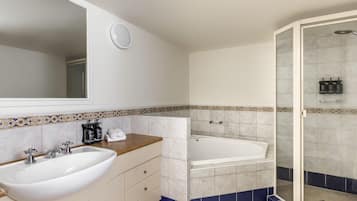Un baño con lavamanos, espejo, tocador y zona de ducha.