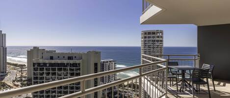 A balcony with a view of the ocean and cityscape.