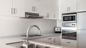 Une cuisine moderne avec des meubles blancs, des appareils en acier inoxydable et un plan de travail en granit.