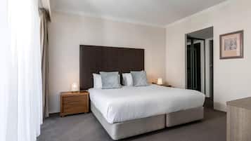 Een slaapkamer met een groot bed, twee nachtkastjes, een hoofdbord en een ingelijste foto aan de muur.