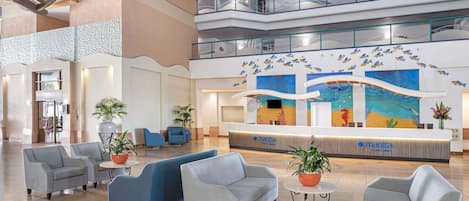 A lobby with a reception desk, seating area, and a high ceiling with a wooden beam structure.