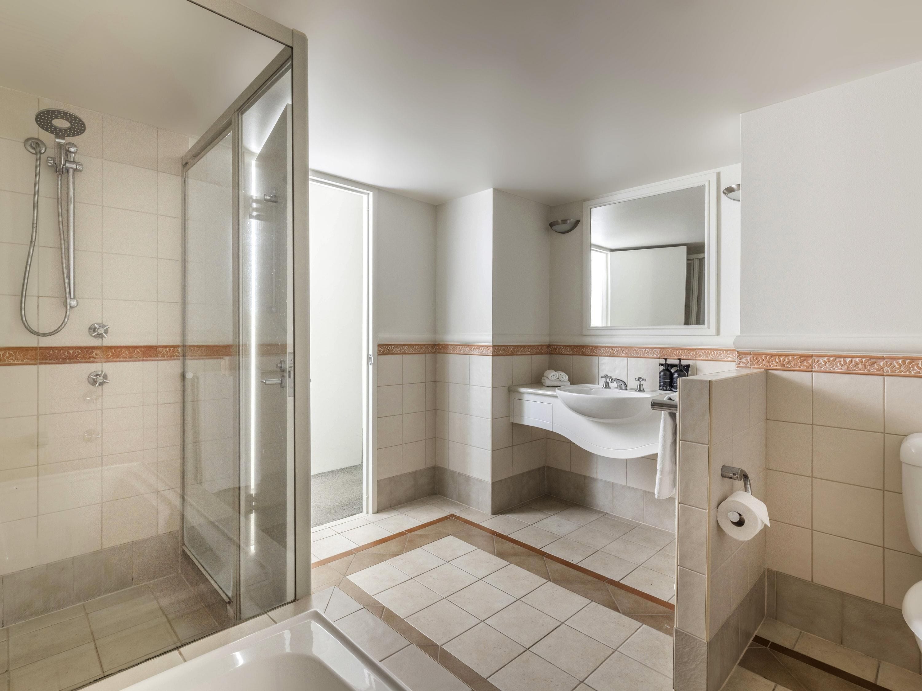 Un baño con cabina de ducha de vidrio, un lavabo con espejo y un inodoro.