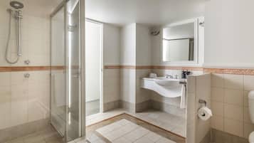 A bathroom with a glass shower enclosure, a sink with a mirror, and a toilet.