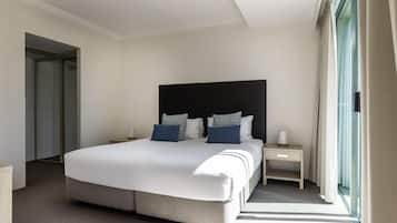 Habitación de hotel con una cama grande, mesitas de noche, un espejo y vistas al exterior.