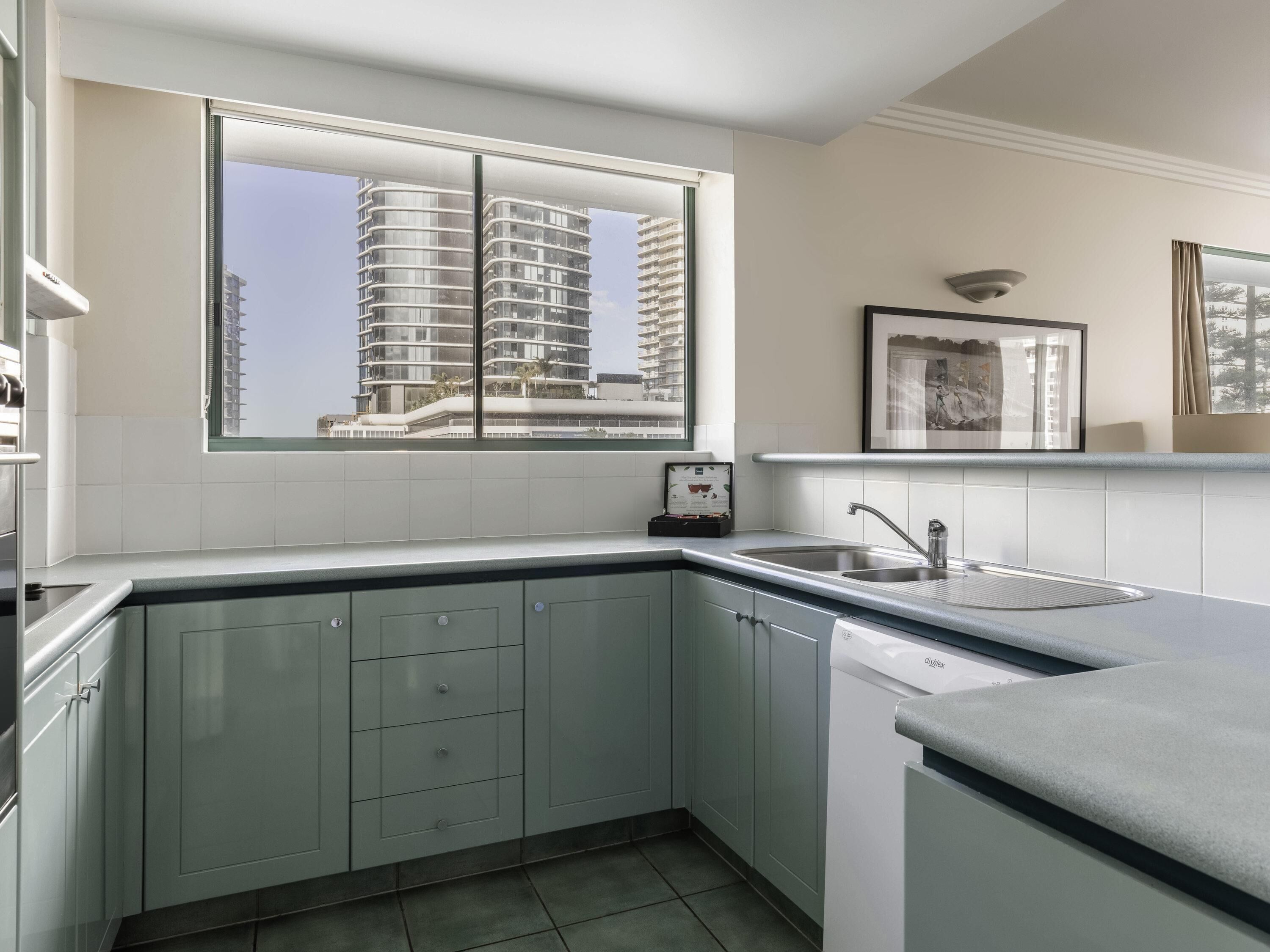 A modern kitchen with a large window, a built-in sink, and a dishwasher.