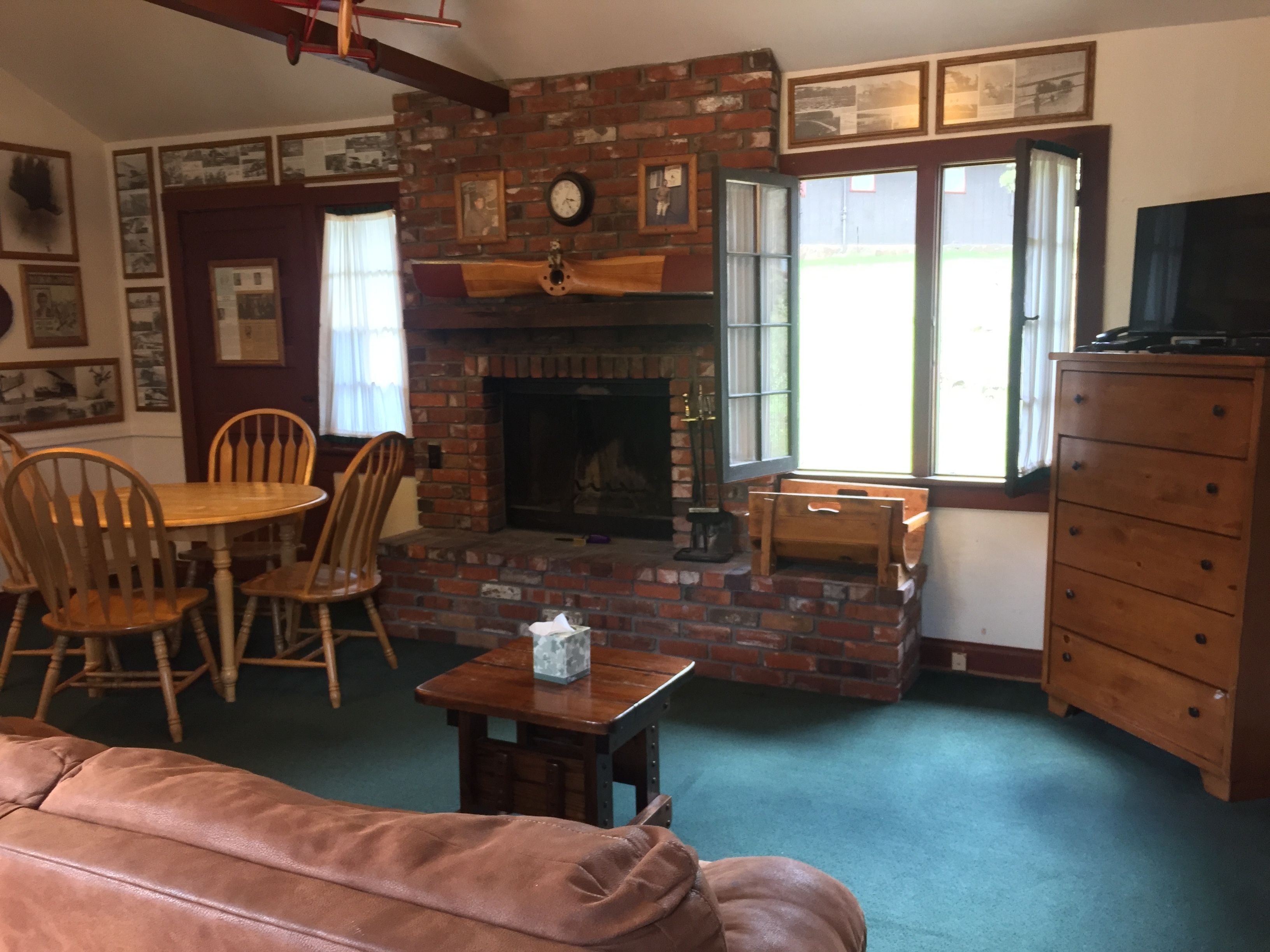 Una sala de estar acogedora con chimenea de ladrillo, muebles de madera y televisor.
