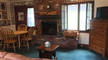Una sala de estar acogedora con chimenea de ladrillo, muebles de madera y televisor.