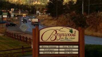 A sign for Brynwood on the river with amenities listed including River Frontage, Free Wi-Fi, Fireplaces, Kitchens, Heated Pool, and Hot Tubs.