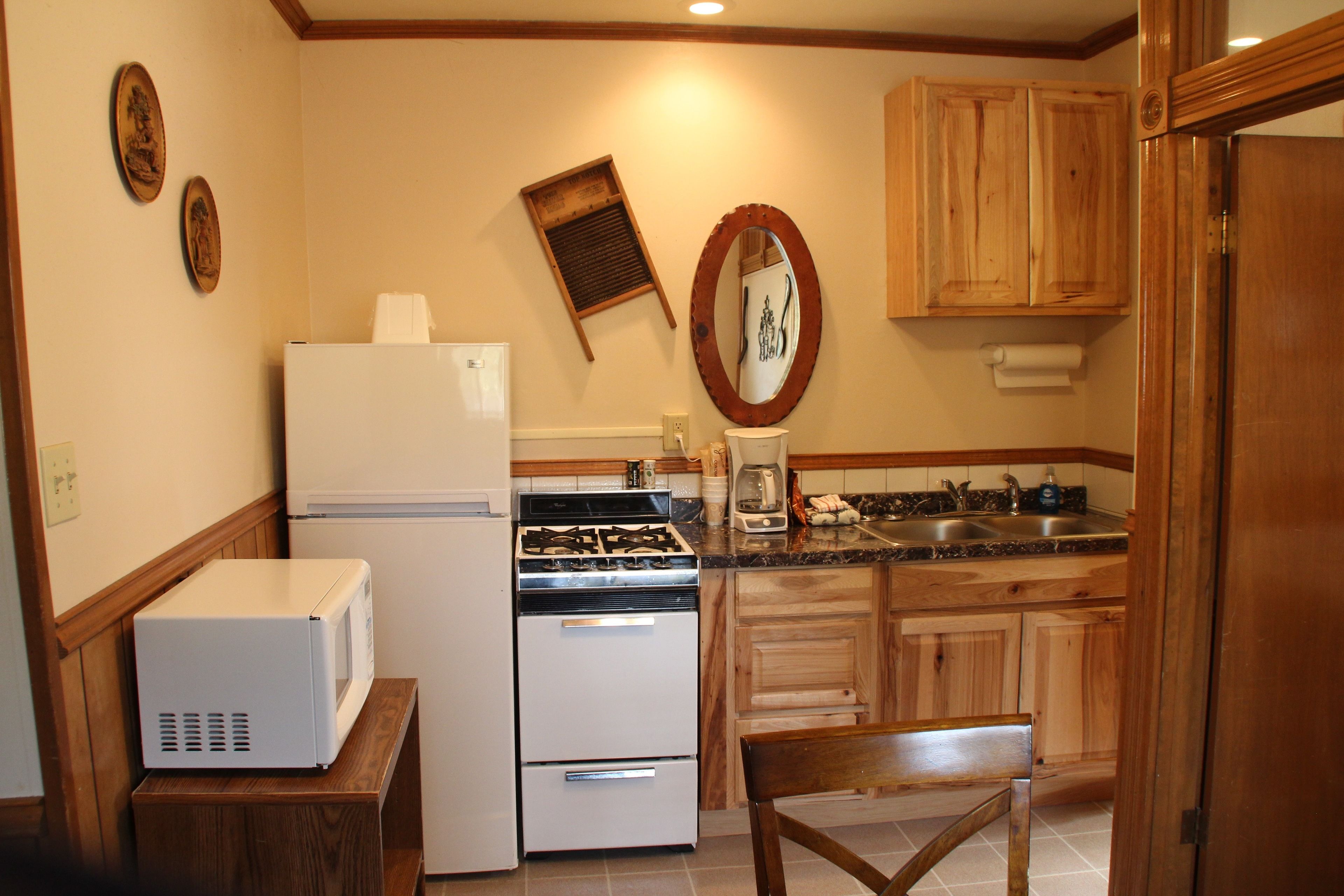Una cocina compacta equipada con refrigerador, estufa, microondas y gabinetes de madera.
