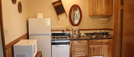 Una cocina compacta equipada con refrigerador, estufa, microondas y gabinetes de madera.