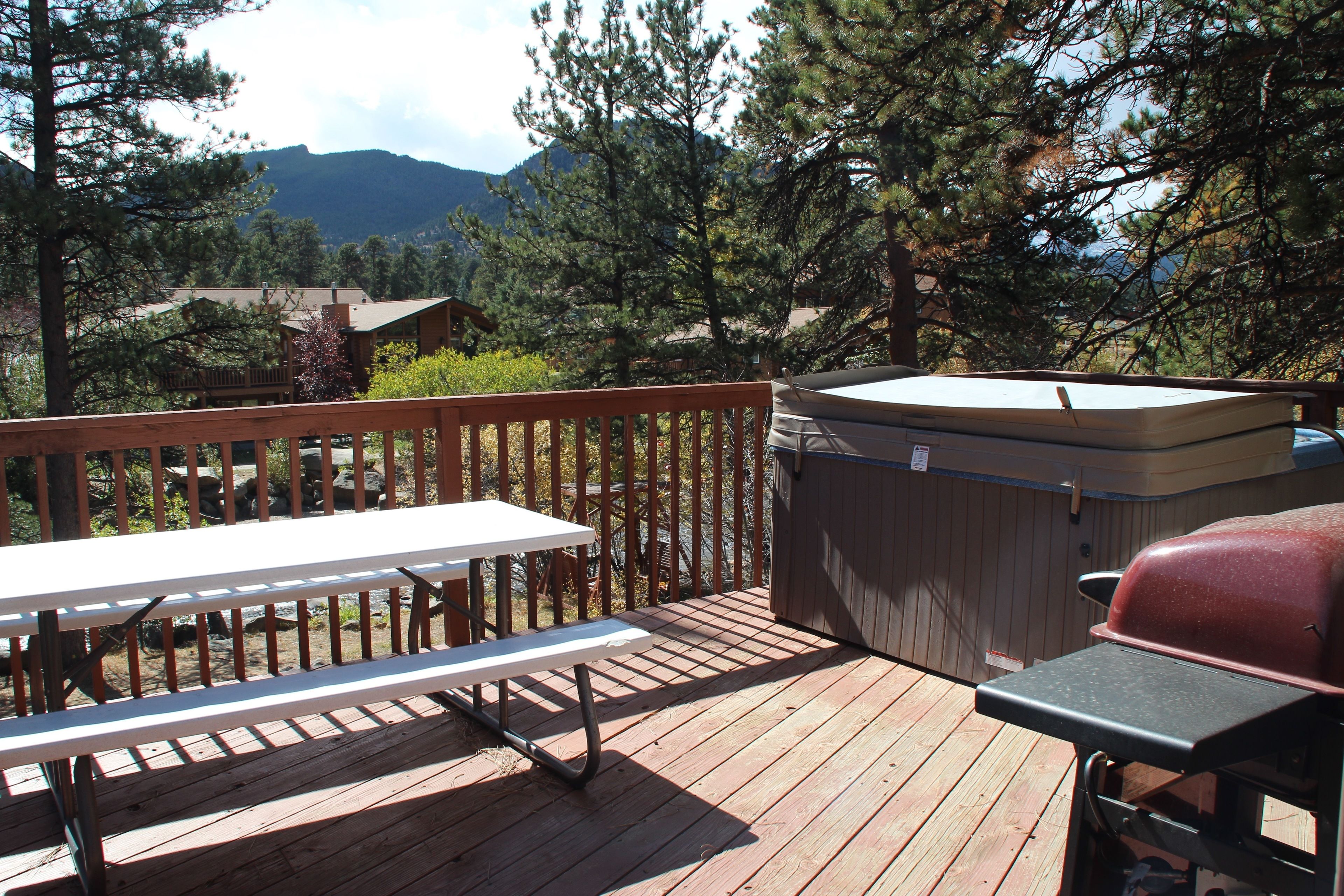 A wooden deck with a picnic table and a barbecue grill.