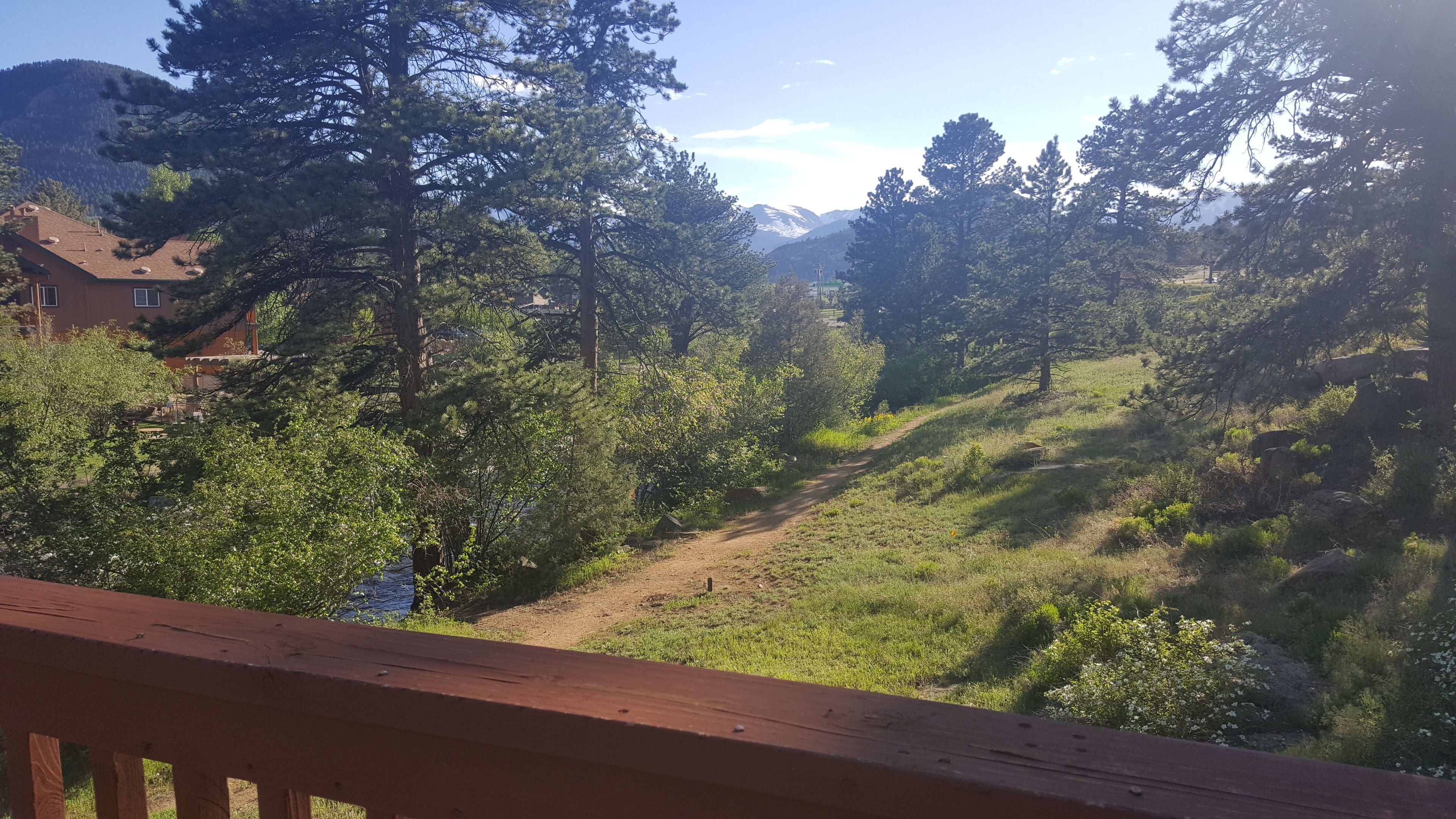 A wooden deck overlooking a mountainous landscape with dense trees and a clear sky.
