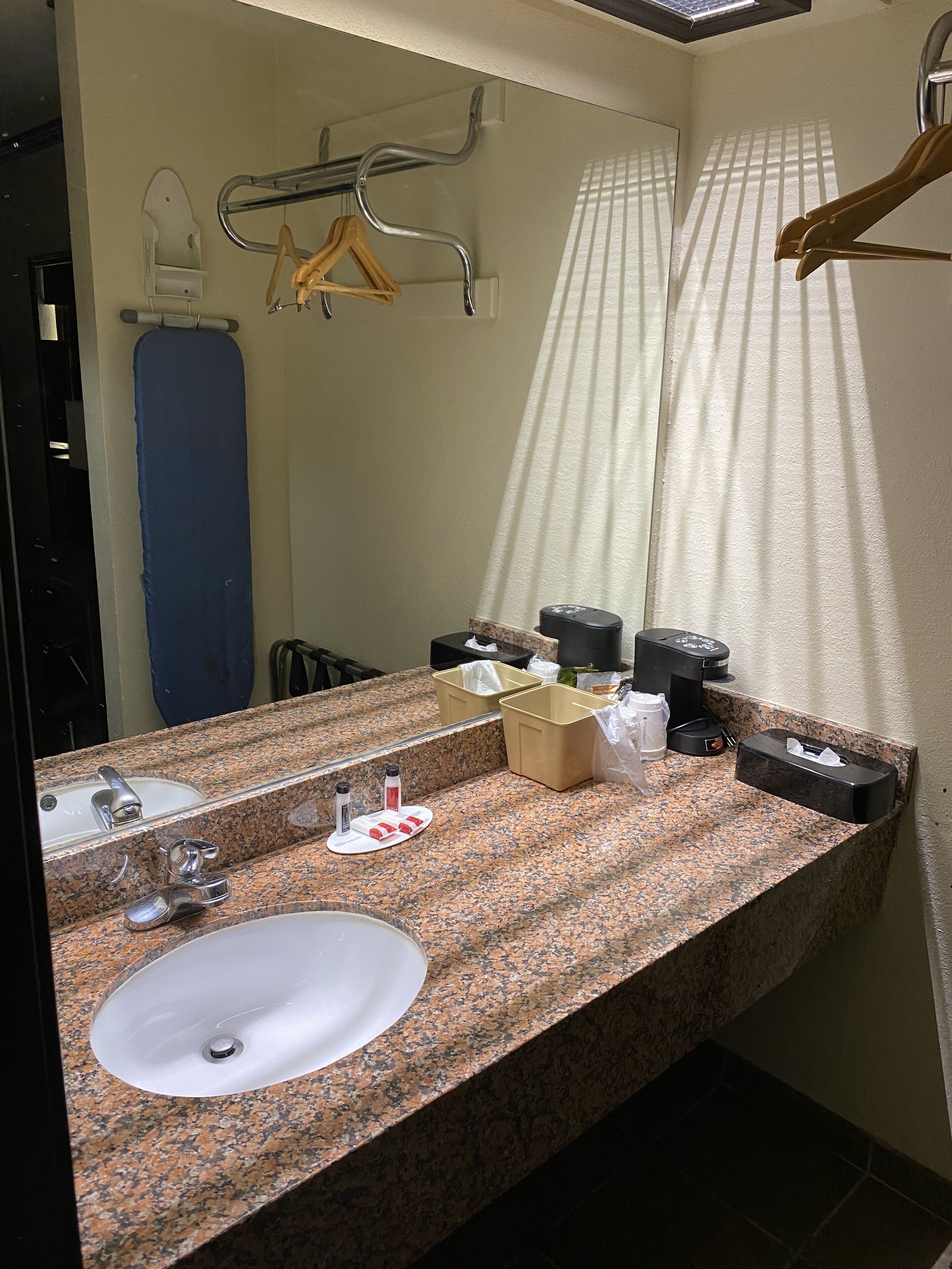 A bathroom with a granite countertop, a white sink, a mirror, a towel rack, and a shower curtain.
