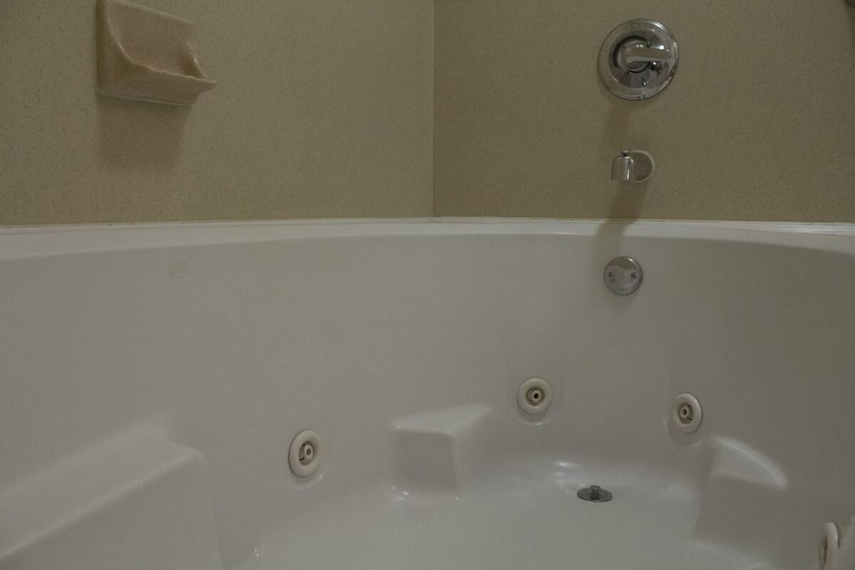 Una bañera con desagüe, grifo y dispensador de pañuelos de pared.