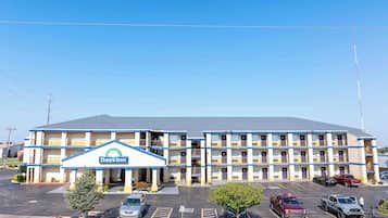 A Days Inn with a two-story building, a parking lot with several cars, and a clear blue sky.