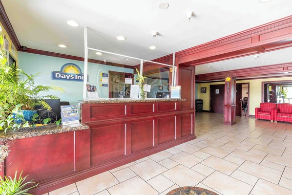 A reception area with a reception desk, a large sign for Days Inn, and a seating area with red chairs.