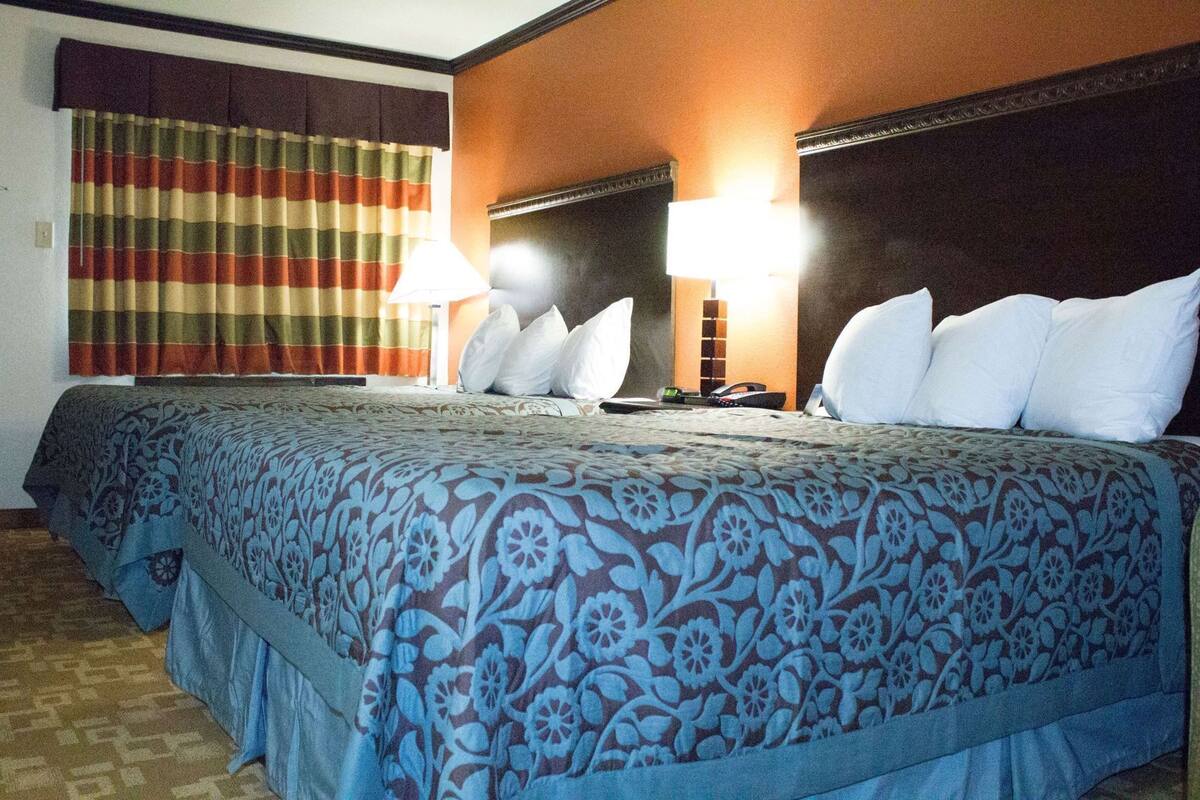 Habitación de hotel con una cama grande, dos lámparas de noche, una cortina a rayas y un cabecero con panel de luz.