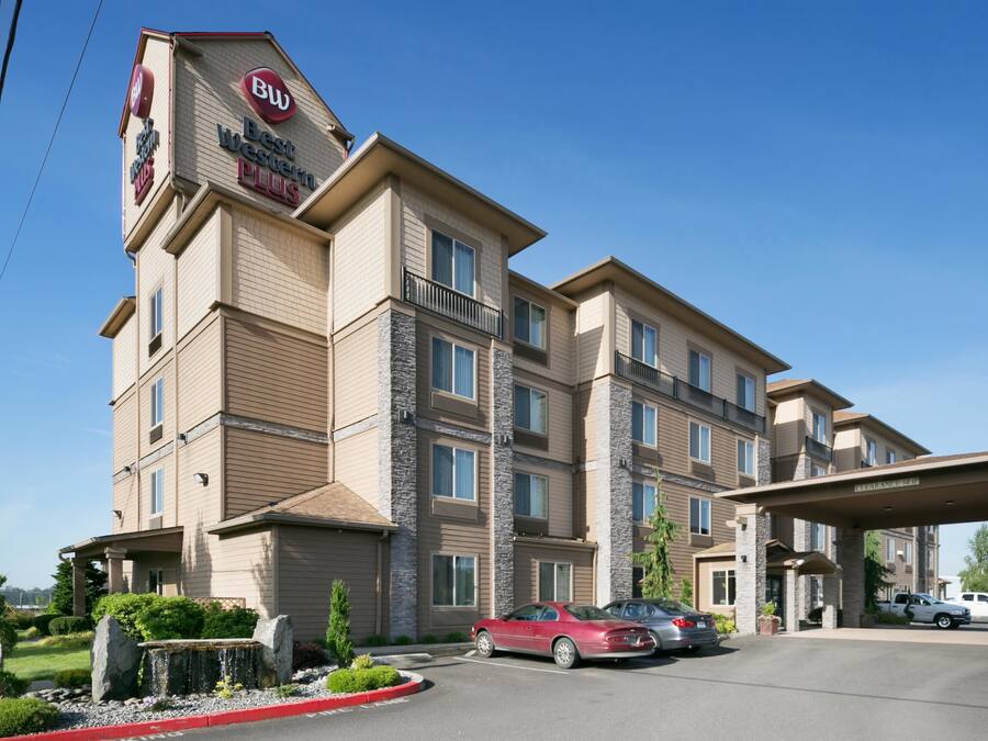 Un hotel de varios pisos con un letrero de 'Best Western Plus', una entrada techada y un estacionamiento con automóviles.