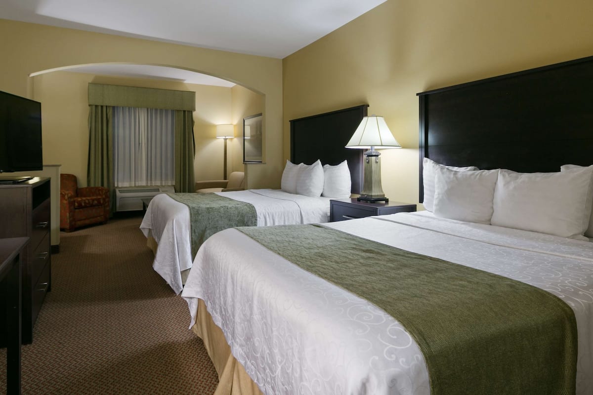 Une chambre d’hôtel avec deux lits, une télévision, un bureau et une chaise.