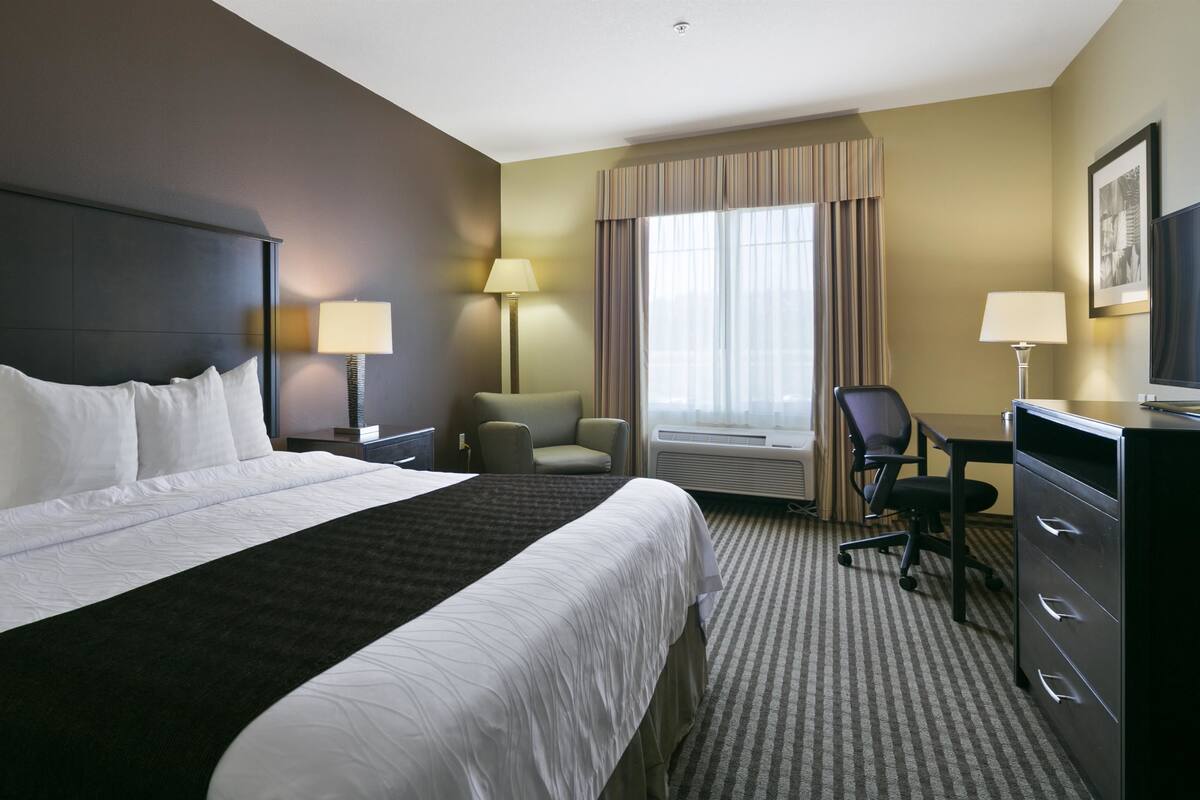 Une chambre d’hôtel avec un grand lit, un bureau, une chaise et un téléviseur.