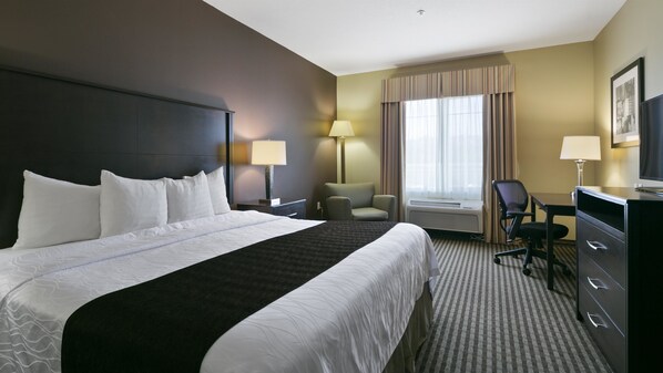 Une chambre d’hôtel avec un grand lit, un bureau, une chaise et un téléviseur.