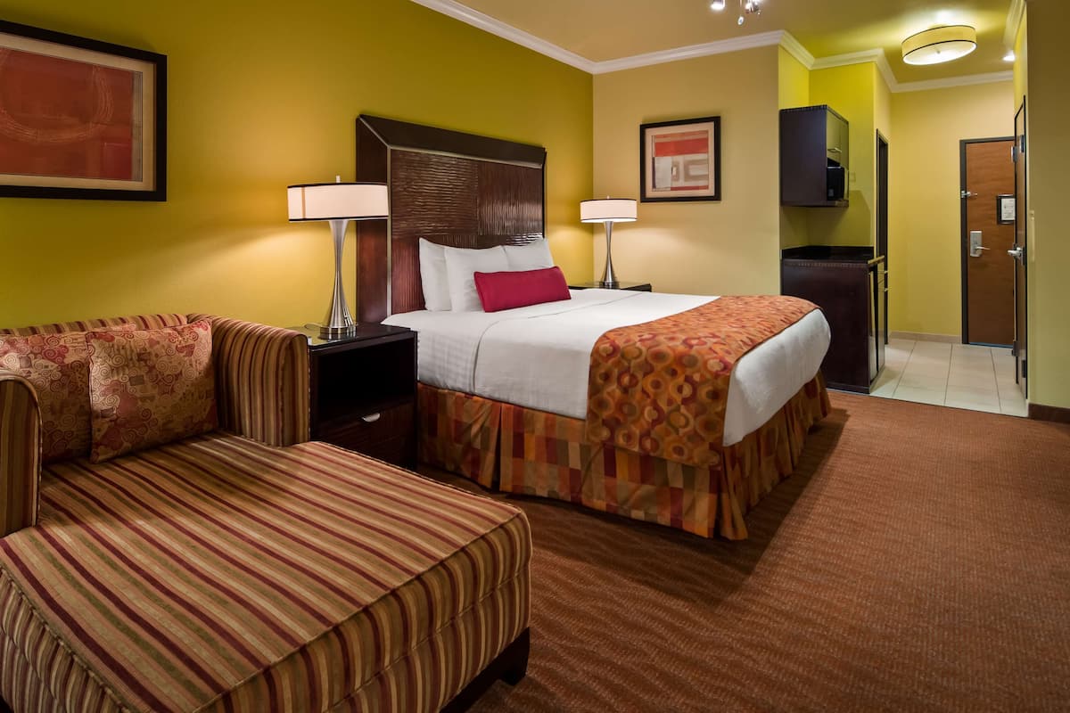 Quarto de hotel com uma cama, um sofá, uma mesa de cabeceira e uma escrivaninha.
