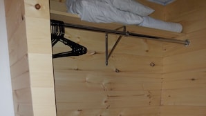 A wooden room with a slanted ceiling, a clothes rack, and a hanging towel. - A Holiday Motel (Maggie Valley)