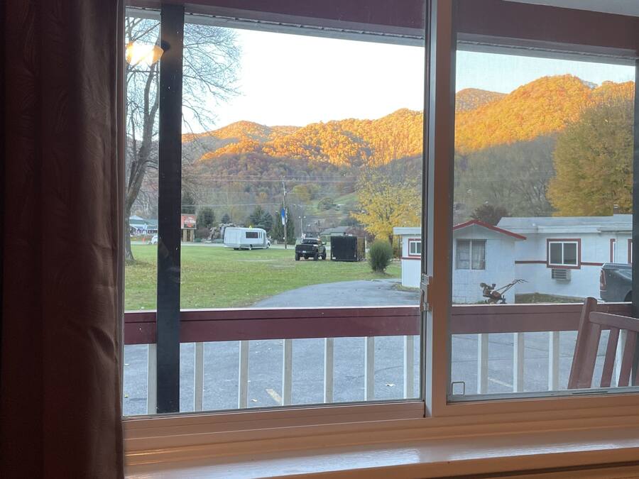 A room with a large window overlooking a residential area and a mountain range.