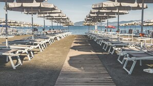 A beachside promenade with rows of sun loungers and umbrellas, leading to the sea.