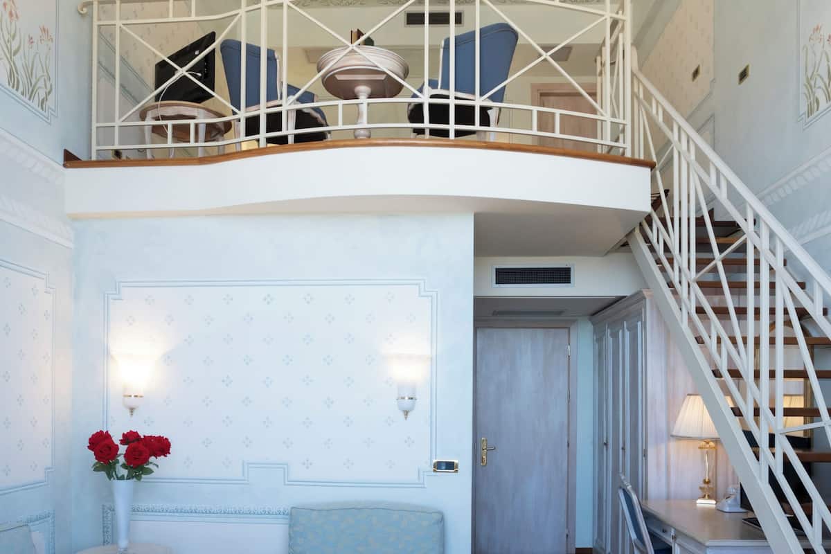 Un salón espacioso con techo alto, una escalera y vistas del piso superior.