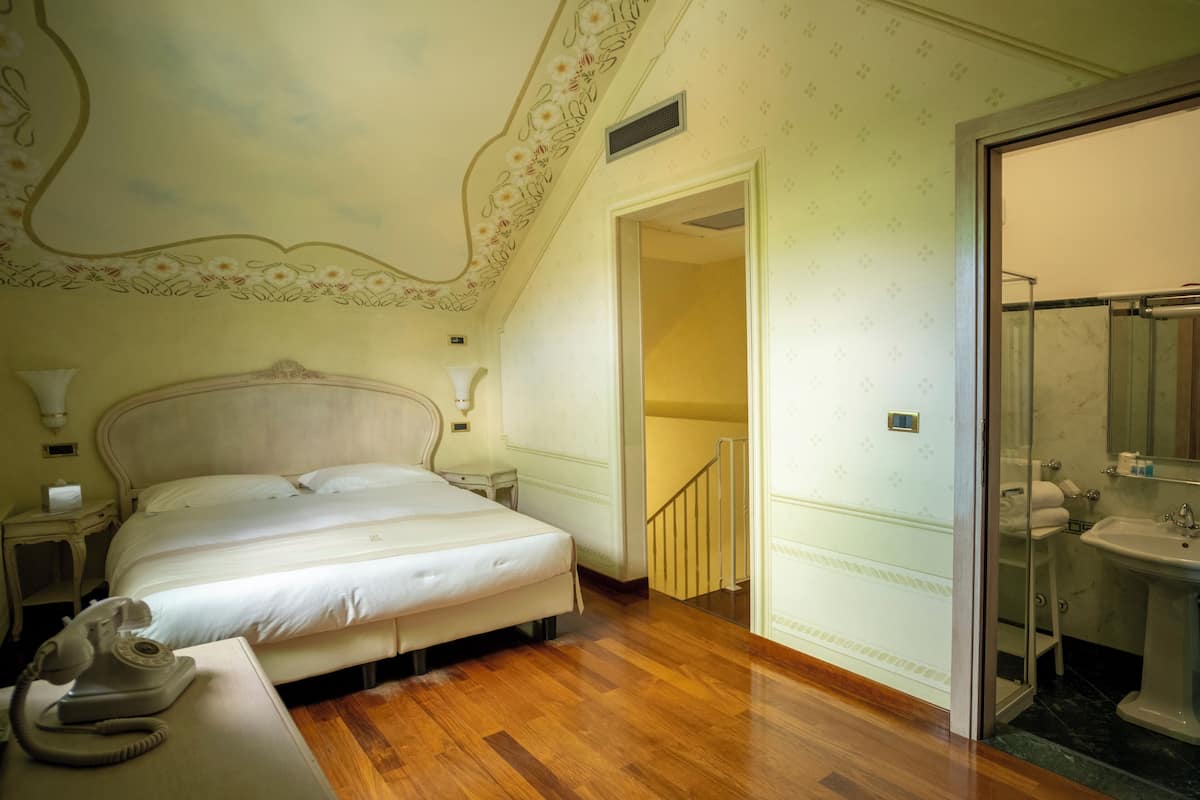 Habitación con cama, mesita de noche y teléfono. Incluye un baño con lavamanos y espejo.