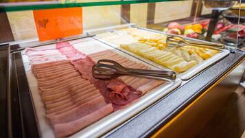 Un buffet proposant une variété de plats, notamment des viandes et des fromages coupés en tranches, présentés sur des plateaux.