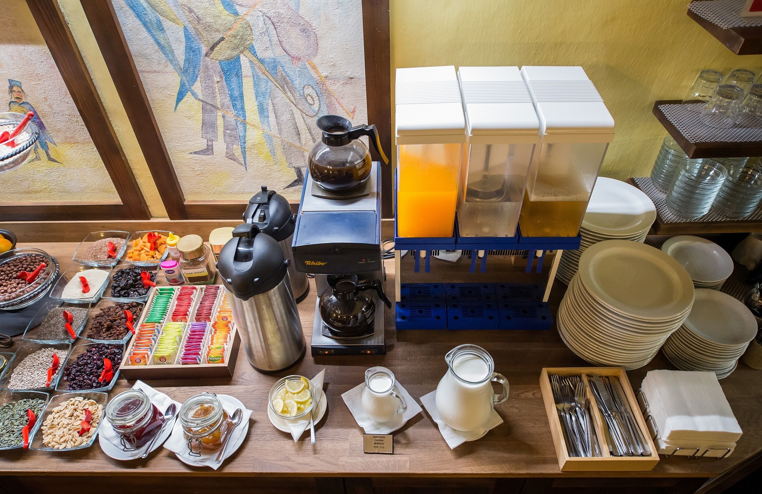A breakfast buffet with various food items, coffee machines, and dining ware.