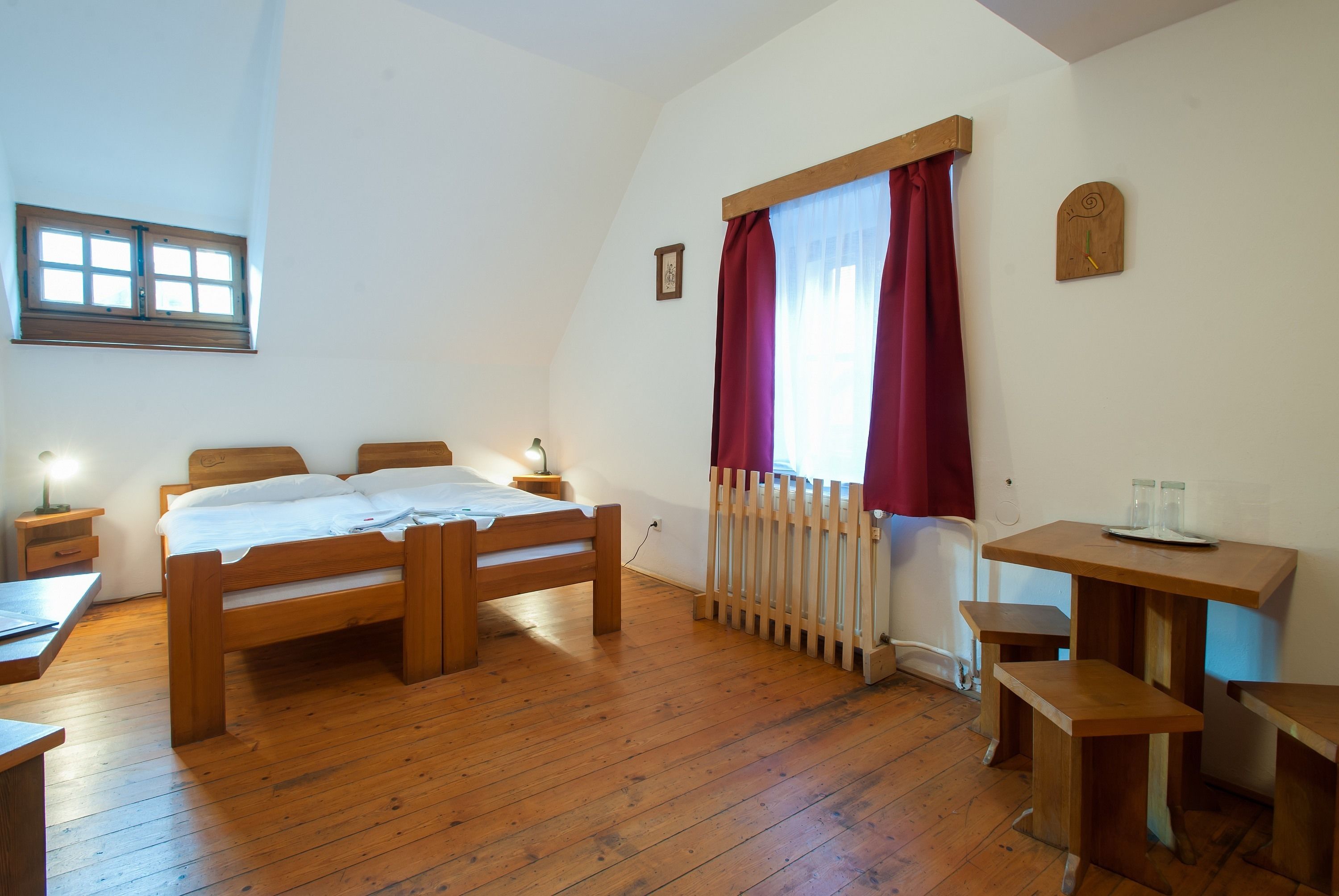 A bedroom with a wooden bed, a desk, and a radiator.